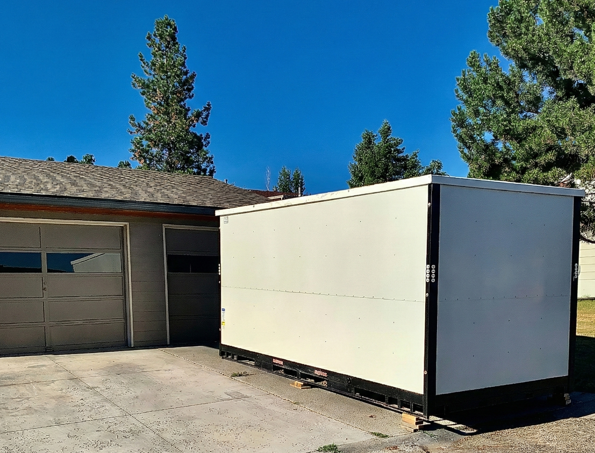 image of a white portable storage in oxnard container in the driveway across from the garage of a house waiting to be unloaded